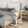 Compact oak wood bed table with a white metal frame, designed for working or eating in bed, with a laptop placed on top.