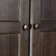 Close-up of Branford Armoire’s solid wood doors with round metal knobs in an antique finish.
