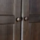 Close-up of Branford Armoire’s solid wood doors with round metal knobs in an antique finish.