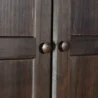Close-up of Branford Armoire’s solid wood doors with round metal knobs in an antique finish.