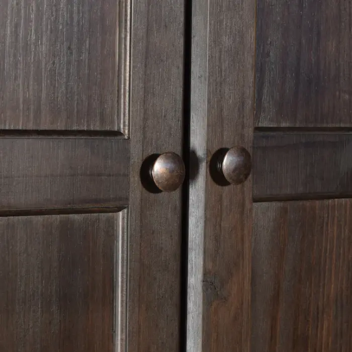 Close-up of Branford Armoire’s solid wood doors with round metal knobs in an antique finish.