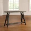 ForgeLine Console Table in Gray with a rustic wood tabletop and black trestle-style base, placed in a bright room with wooden flooring