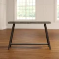 ForgeLine Console Table in Gray with a weathered wood tabletop and black angled legs, set in a bright room with wooden flooring.