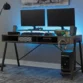Roco Elite Gaming Desk featuring dual monitors, gaming accessories, and ambient lighting setup.