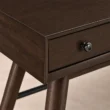 Close-up of Walnut finish, drawer front and round metal knob on Script Trestle Writing Desk
