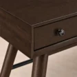 Close-up of Walnut finish, drawer front and round metal knob on Script Trestle Writing Desk