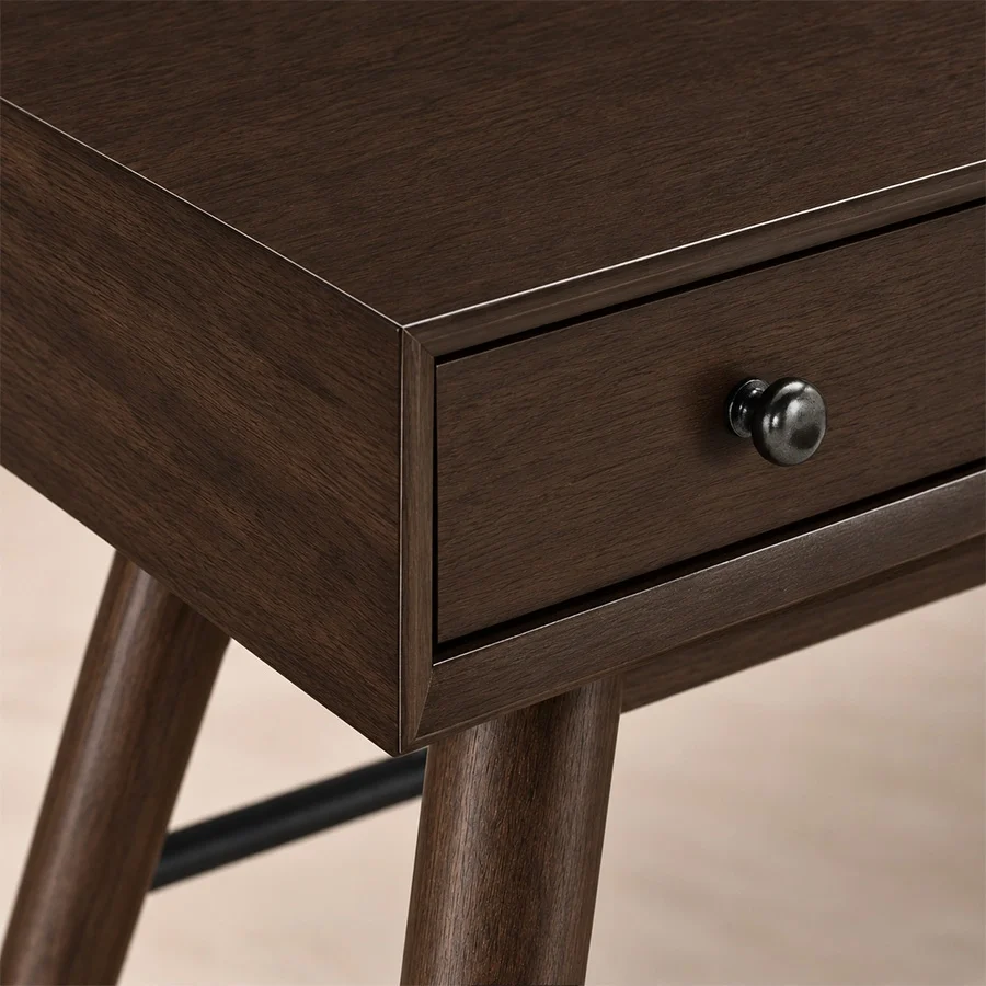 script-trestle-writing-desk-walnut-closeup-detail-view. Close-up of Walnut finish, drawer front and round metal knob on Script Trestle Writing Desk