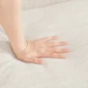 Close-up shot of a hand gently pressing into the soft fabric of the Versatile Square Arm Sofa, highlighting the cushion's comfort.