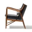 Incurve Leatherite Chair – Side view of a black leatherite lounge chair with a wooden frame and curved armrests