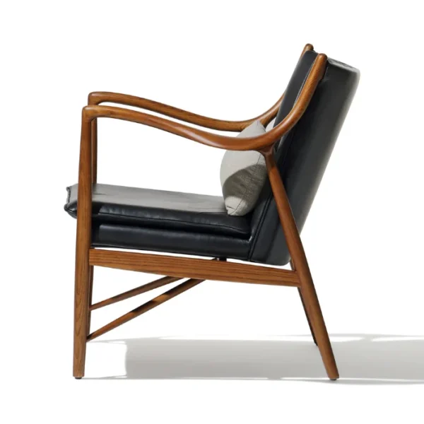 Incurve Leatherite Chair – Side view of a black leatherite lounge chair with a wooden frame and curved armrests Incurve Leatherite Chair – Side view of a black leatherite lounge chair with a wooden frame and curved armrests
