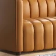 Side view close-up of camel-colored sofa armrest with vertical fluted seat design and soft leather finish.