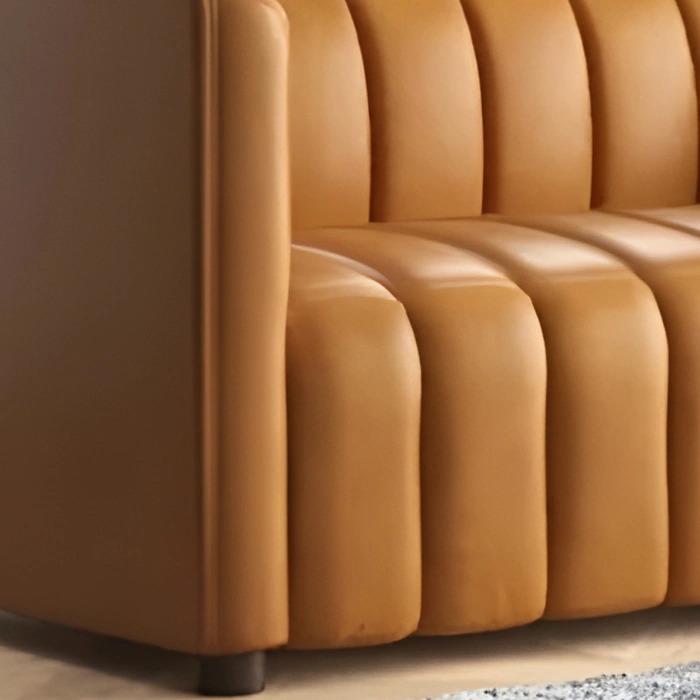 Side view close-up of camel-colored sofa armrest with vertical fluted seat design and soft leather finish.