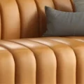 Close-up of leather upholstery showing deep fluted stitching and smooth padded texture.