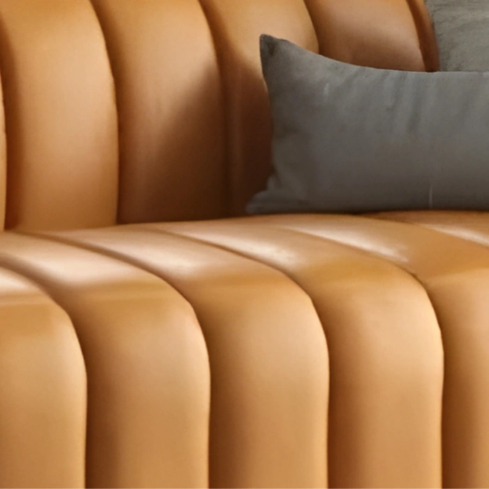 Close-up of leather upholstery showing deep fluted stitching and smooth padded texture.