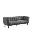 Full view of dark grey tufted fabric 3-seater on white, tapered wooden legs.