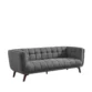 Full view of dark grey tufted fabric 3-seater on white, tapered wooden legs.