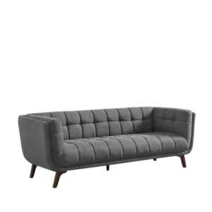 Full view of dark grey tufted fabric 3-seater on white, tapered wooden legs.