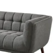Close-up of dark grey tufted fabric sofa arm and seat with plush cushioning.