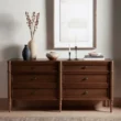 Wooden dresser with six drawers in walnut finish, styled with minimalist décor and ceramic vases.