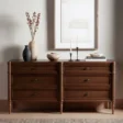 Wooden dresser with six drawers in walnut finish, styled with minimalist décor and ceramic vases.