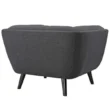 Back view of dark grey tufted armchair with smooth upholstery and tapered black mid-century legs.