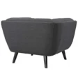 Back view of dark grey tufted armchair with smooth upholstery and tapered black mid-century legs.