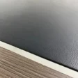 Close-up of textured black leather desk inlay bordered by metallic trim and walnut veneer.