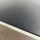 Close-up of textured black leather desk inlay bordered by metallic trim and walnut veneer.