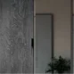 Close-up of charcoal wood sliding door with recessed pull beside a mirrored panel—modern wardrobe detail
