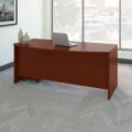 Maghony-finish bow-front office desk staged by window with laptop and minimalist décor.