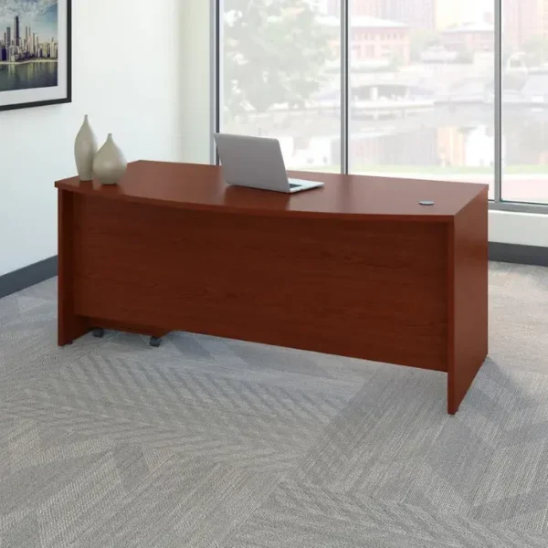 Maghony-finish bow-front office desk staged by window with laptop and minimalist décor.