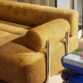 Close-up of ochre fabric sofa armrest with cylindrical cushion.