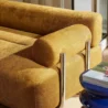 Close-up of ochre fabric sofa armrest with cylindrical cushion.