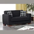 Room setting with compact black 2-seater and two plaid throw pillows.