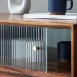 Close-up of fluted glass sliding door with brass knob, blue mug and book above.