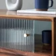 Close-up of fluted glass sliding door with brass knob, blue mug and book above.