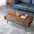 Living room scene with walnut coffee table, fluted glass doors, brass-capped legs, blue sofa.