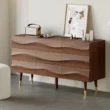 Nordic Haven Dresser – angled view of wooden dresser with wave-textured drawers and brass-accented legs.