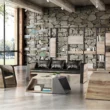 Industrial-style office lounge scene with wood-grain sided 3-seater sofa and black cushions, paired with geometric coffee table and shelving in the background.