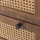 Detailed shot of cane drawer front with round black knob.