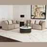 Two curved loveseats arranged in an L-shape around a black-and-gold round coffee table in a bright living room.