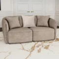 Two-seater taupe loveseat with rounded arms and three soft cushions in a white-paneled modern living room.
