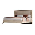 Three-quarter view of modern upholstered bed with ribbed cream frame, slim metal legs, elevated design.
