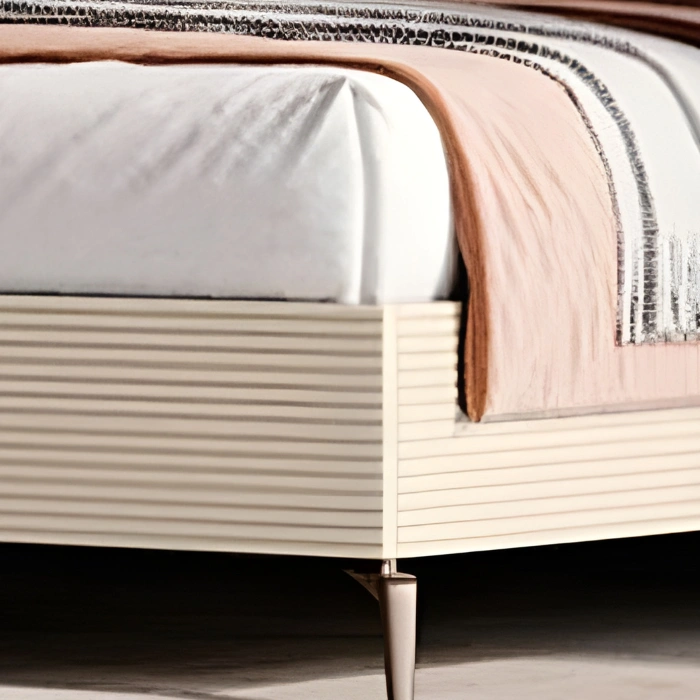 Close-up of ribbed cream side panel, mattress corner, and tapered metal leg with throw blanket