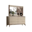 Six-drawer cream dresser on slim legs with framed mirror; ribbed fronts and styled vases reflected.
