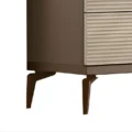 Lower corner close-up highlighting ribbed drawers and tapered metal legs in warm bronze finish.