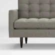 close view of grey ofa showing rmrest and wooden legs