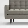 close view of grey ofa showing rmrest and wooden legs