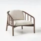Angled view of wooden armchair with beige cushions