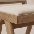Close-up of the cream upholstery, seat edge and natural wood frame detailing